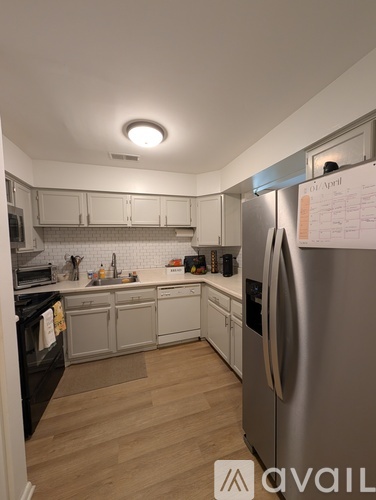 A kitchen with a refrigerator, sink, and cabinets.