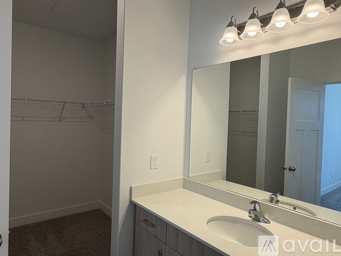 A bathroom with a sink, mirror, and lighting fixture.
