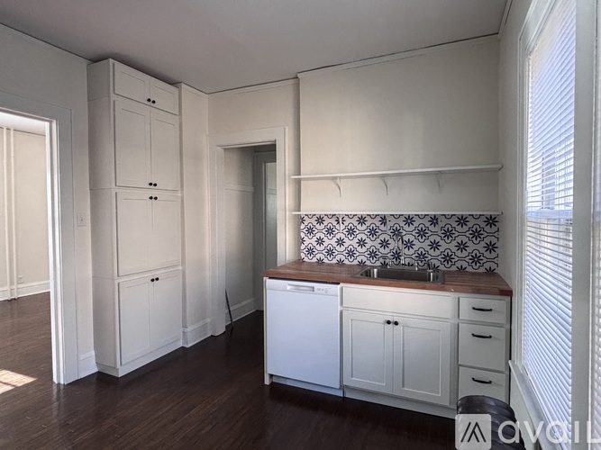 A kitchen with white cabinets and a patterned backsplash.