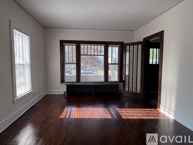 A room with wooden floors and a window with a view of trees.