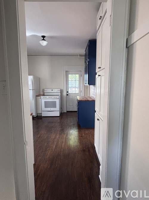 A kitchen with white cabinets and a blue trash can.