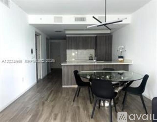 A modern dining room with a glass table and black chairs.