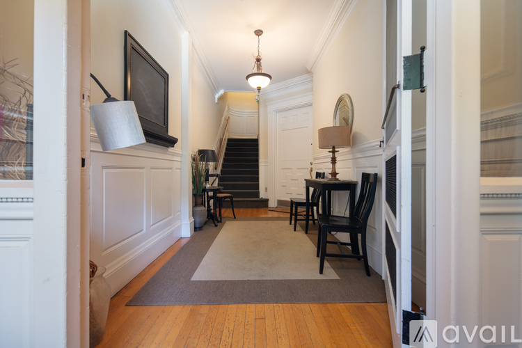 A hallway with a staircase and a table with chairs.