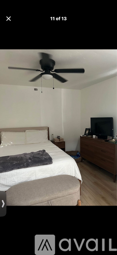 A bedroom with a bed, a ceiling fan, and a dresser with a flat screen TV.