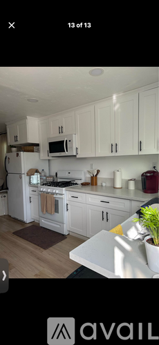 A kitchen with white cabinets and a white microwave above the stove.