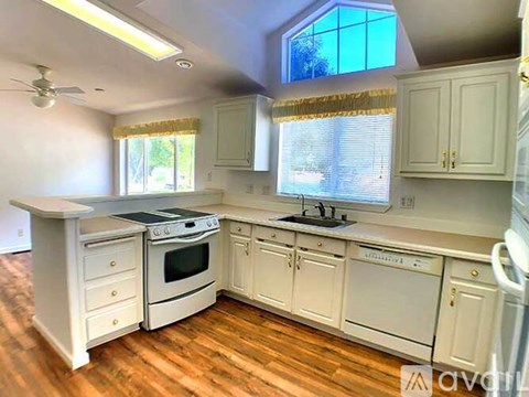 A kitchen with white cabinets and a wooden floor.