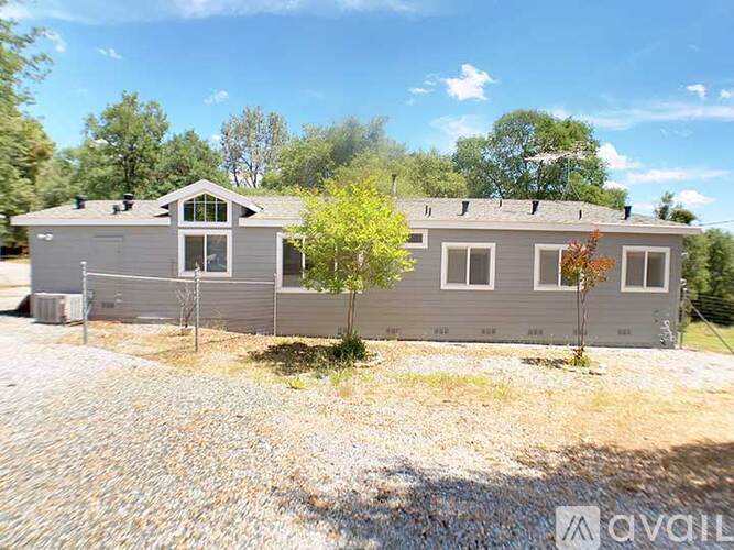 A grey house with a tree in front of it.