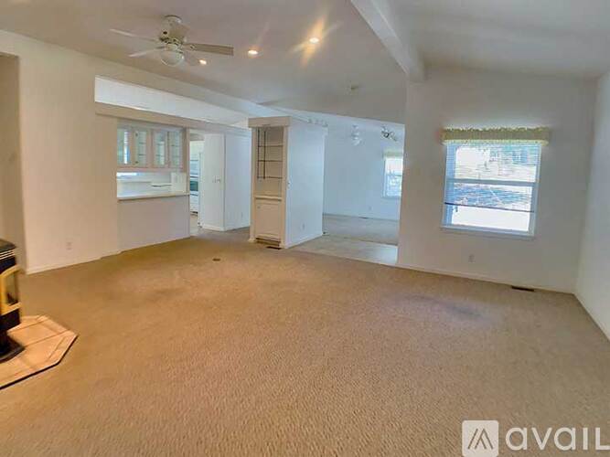 A spacious room with a ceiling fan and two windows.