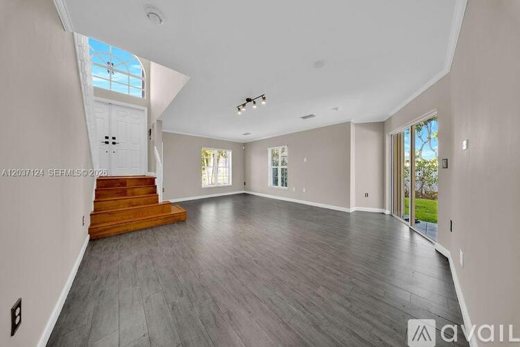 A spacious room with wooden stairs leading to a skylight.