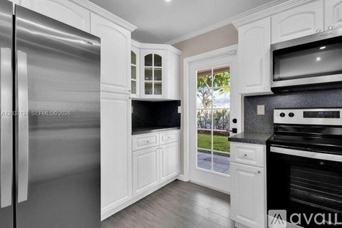 A kitchen with white cabinets and a stainless steel refrigerator.