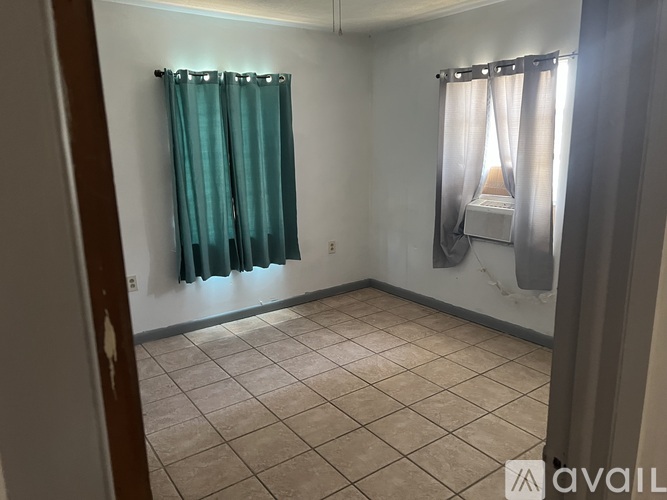 A room with a window covered by a white curtain and a blue curtain.