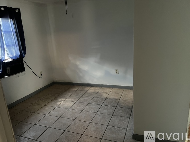 A room with a tiled floor and a window on the left side.