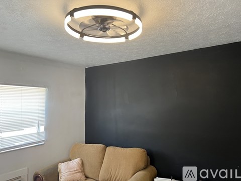 A living room with a beige couch and a ceiling fan.