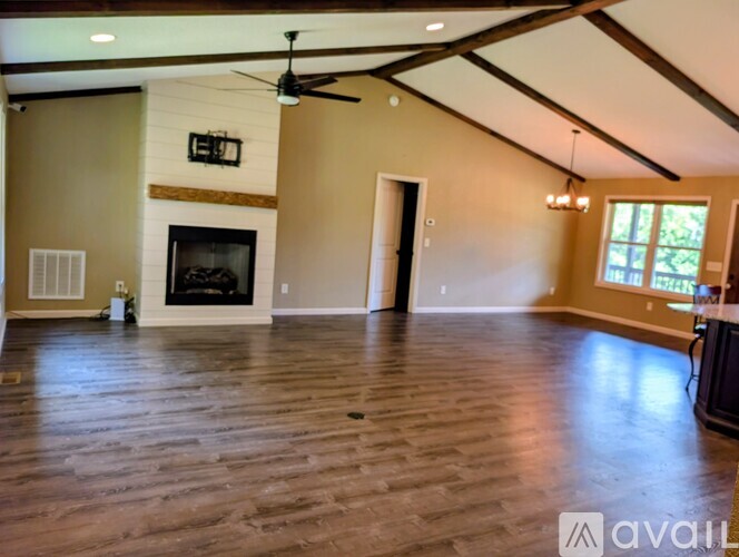 A spacious living room with a fireplace and a ceiling fan.