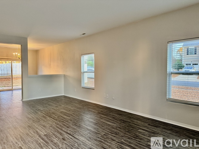 A spacious room with wooden flooring and a large window.