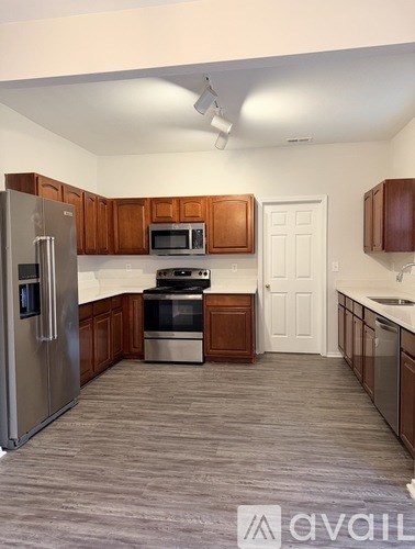 A kitchen with a refrigerator, microwave, oven, and sink.