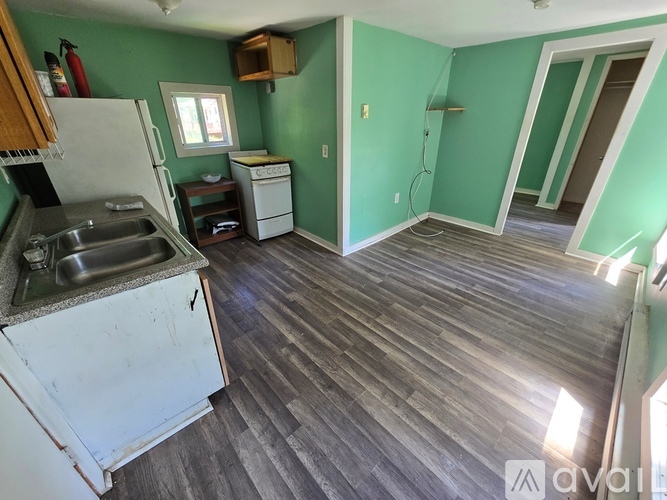 A kitchen with a white fridge and a white dishwasher with a green wall.