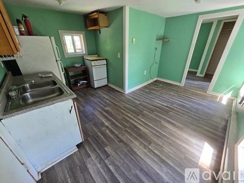 A kitchen with a white fridge and a white dishwasher with a green wall.