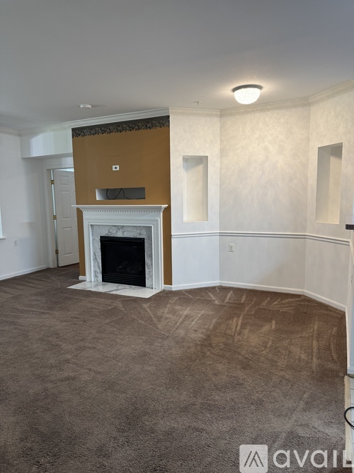 A living room with a fireplace and a brown carpet.
