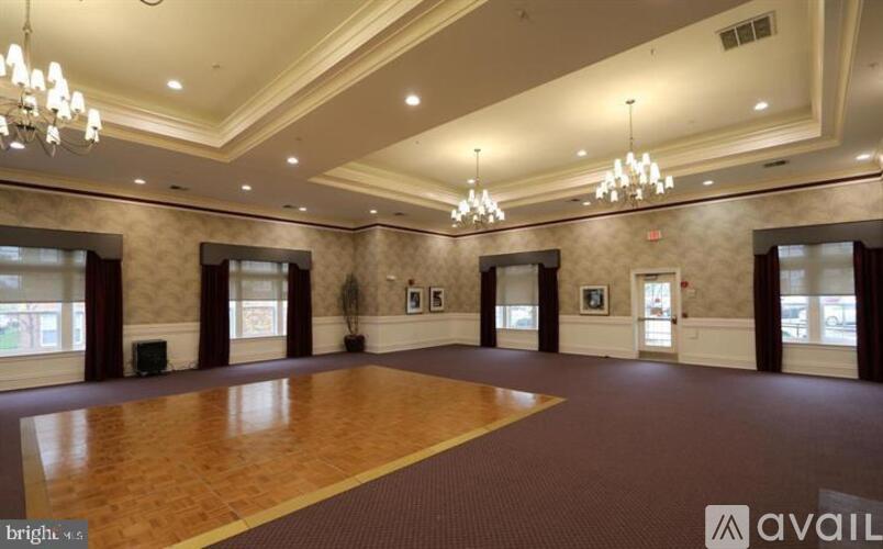 A spacious room with a wooden floor and a chandelier hanging from the ceiling.