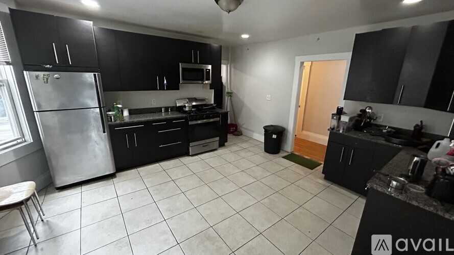 A kitchen with black cabinets and a stainless steel refrigerator.