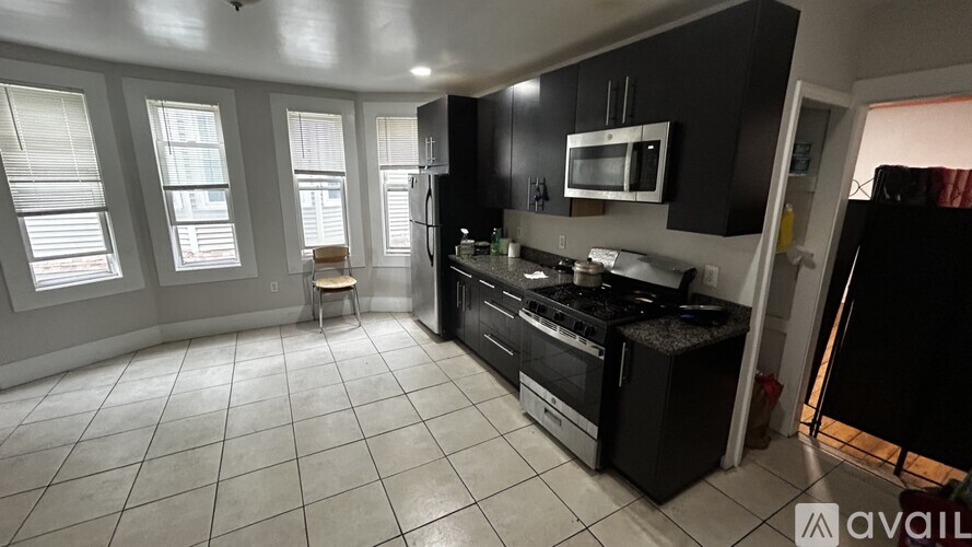 A kitchen with black cabinets and a white microwave.