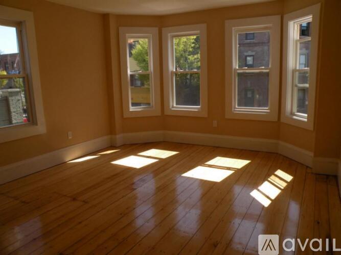 A room with wooden floors and three windows.