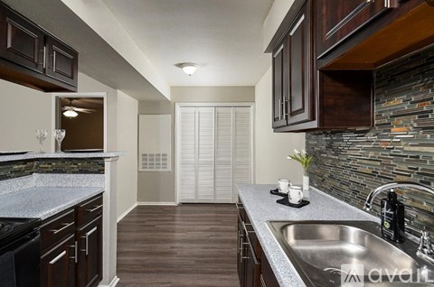 A kitchen with a sink, a counter, and a wall of cabinets.