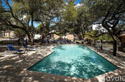 A pool surrounded by trees and chairs.