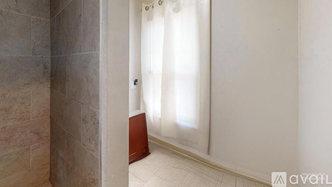 A bathroom with a shower curtain and tiled walls.