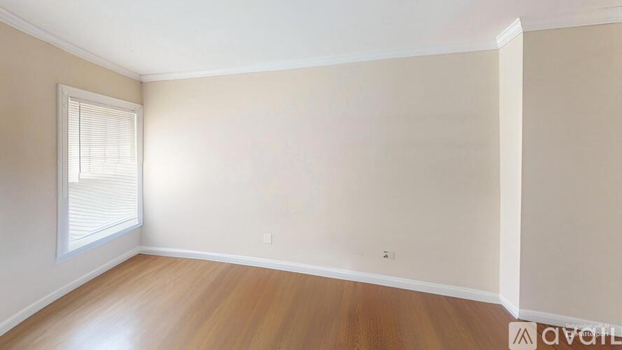 A room with wooden flooring and a window with blinds.
