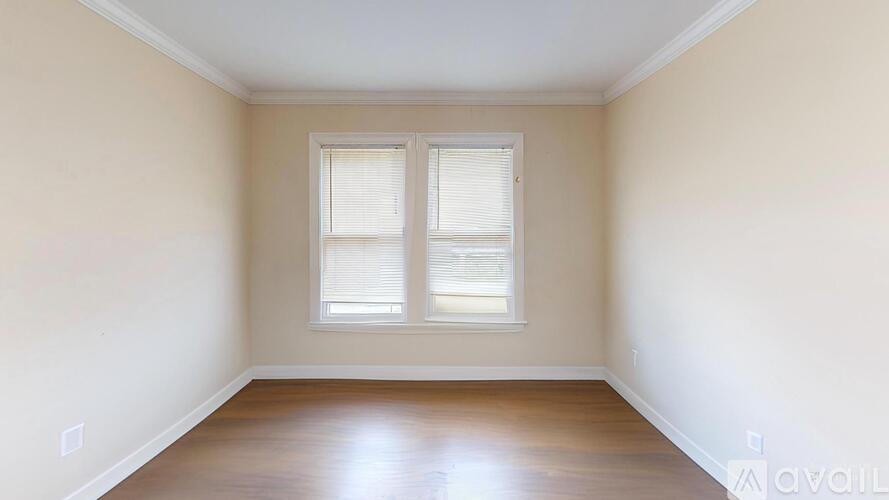 A room with wooden floors and a window with blinds.