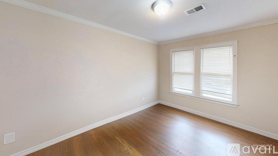 A room with wooden flooring and a window with blinds.
