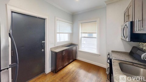 A kitchen with a black fridge, wooden cabinets, and a sink.