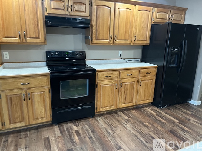 A kitchen with wooden cabinets and black appliances.