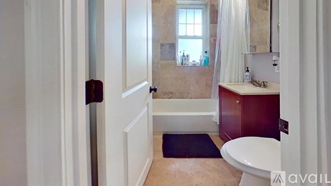 A bathroom with a toilet, sink, and a window.