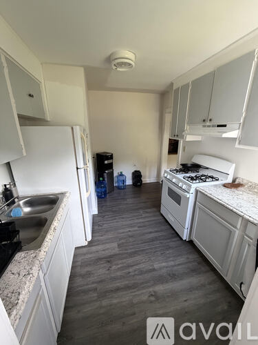 A kitchen with white cabinets and a wooden floor.