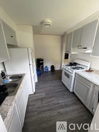 A kitchen with white cabinets and a wooden floor.