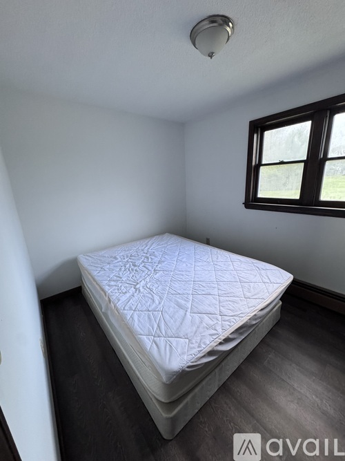 A bed with a white cover is in a room with a window.