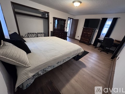 A bedroom with a large bed and a chair.