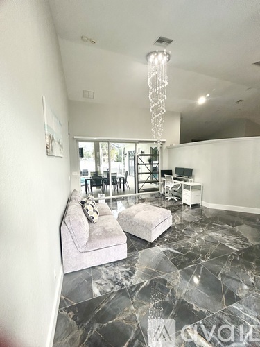 A living room with a grey couch and a chandelier.
