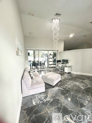 A living room with a grey couch and a chandelier.