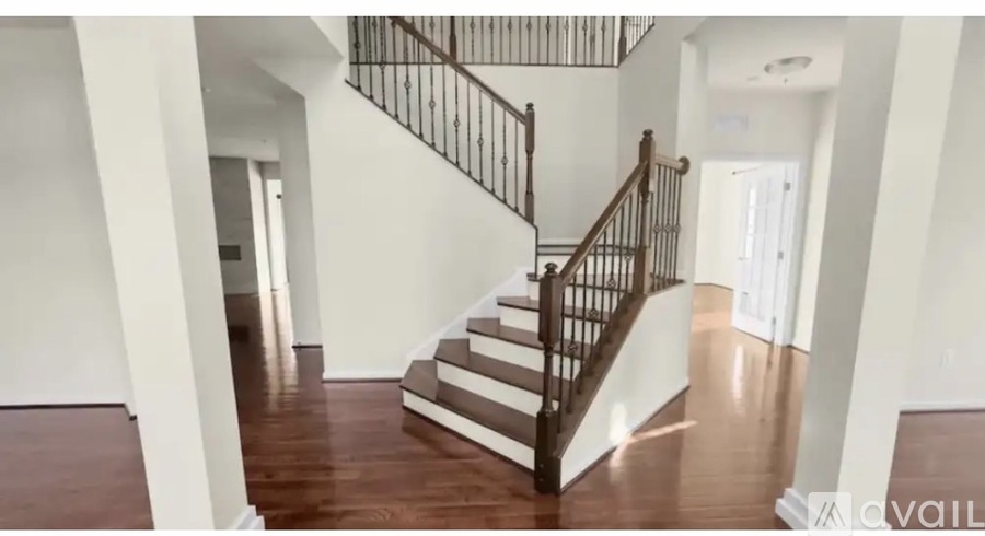 A staircase with a wooden handrail and steps leading up to a landing with a white door.