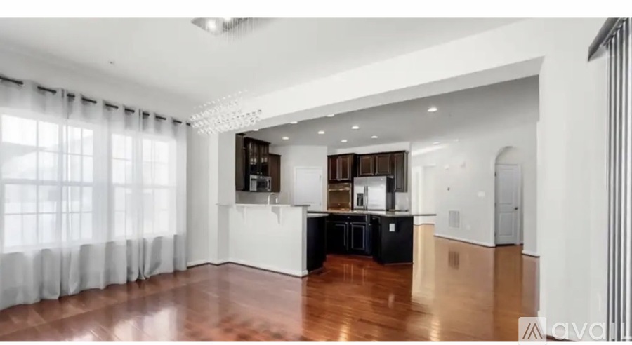 A spacious kitchen with dark wood floors and white cabinetry.