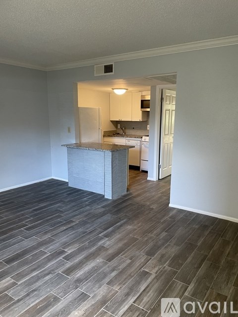 A kitchen area with a counter and cabinets is visible through an open door.