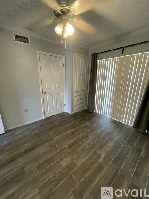 A room with a ceiling fan and wooden flooring.