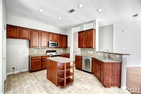 A kitchen with wooden cabinets and a white island.