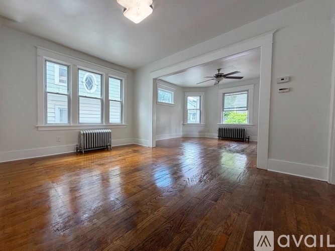 A spacious room with wooden floors and a ceiling fan.