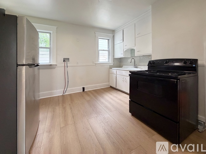 A kitchen with a black stove top oven and wooden flooring.