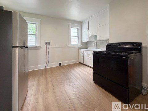 A kitchen with a black stove top oven and wooden flooring.